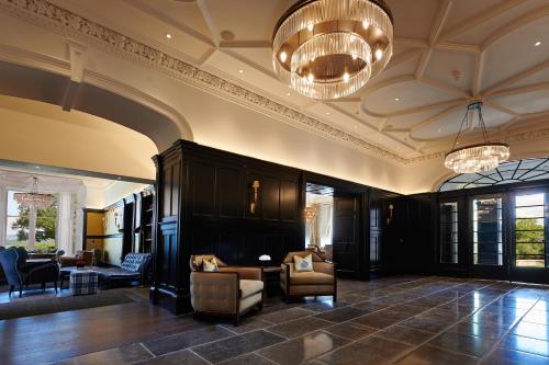 a lobby with chairs and a couch and a chandelier at Cameron House on Loch Lomond in Balloch
