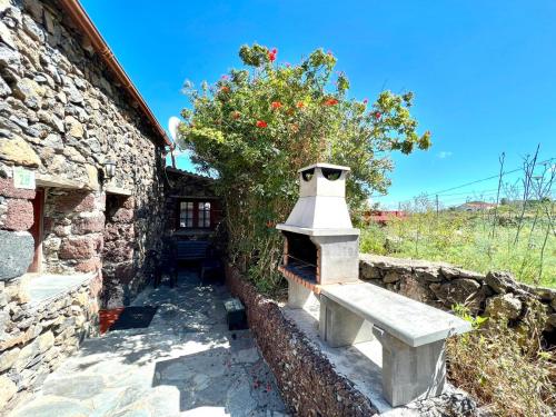 un edificio de piedra con un banco junto a una pared en Casa rural con 2 dormitorios con barbacoa y preciosa vista en Mocanal