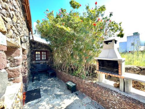 una casa de piedra con chimenea al aire libre en un patio en Casa rural con 2 dormitorios con barbacoa y preciosa vista en Mocanal