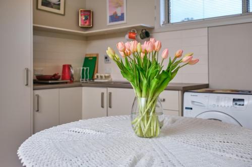 a vase of pink tulips sitting on a table at Breeza Haven - Your Home Away From Home in Kingston