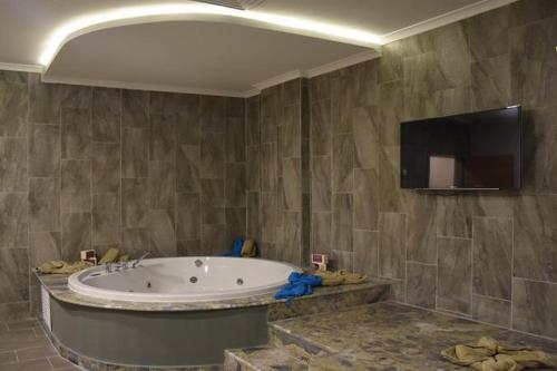 baño con bañera y TV de pantalla plana. en JURA HOTELS ALTINOLUK THERMAL, en Avcılar