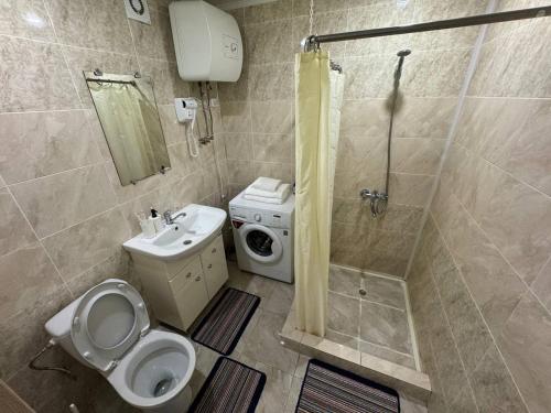 y baño con aseo, ducha y lavamanos. en Светлые и уютные апартаменты с выходом в центральный парк, en Kostanái