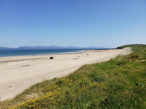 a sandy beach with people in the water at Traditional Cosy Cottage in Louisburgh