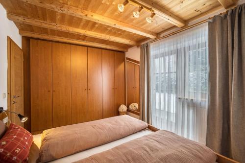 um quarto com uma cama e uma grande janela em Mountain Lodge Antholz em San Giuseppe in Anterselva