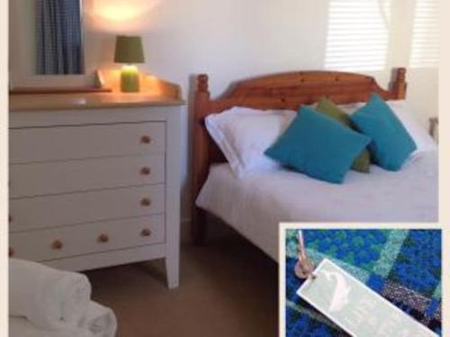a bedroom with a dresser and a bed with blue pillows at Apple Tree Apartment in Pembroke