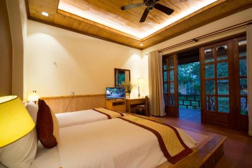 a bedroom with a large bed with a ceiling fan at Paradiso Phu Quoc Resort in Phu Quoc