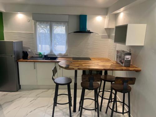 una cucina con bancone in legno e sgabelli da bar di Sublime appartement T3 a Pierrelaye
