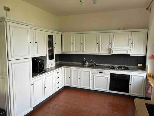 a kitchen with white cabinets and black appliances at Villa Casa Camelia in Traumlage in San Bartolomeo