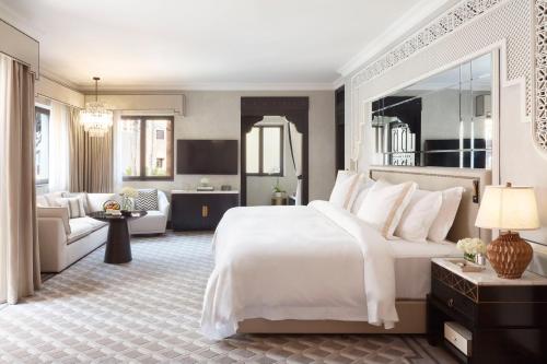 a bedroom with a large white bed and a living room at Jumeirah Dar Al Masyaf Dubai in Dubai