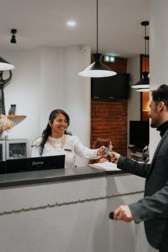 a woman shaking hands with a man at a counter at Hotel Albert 1er in Toulouse