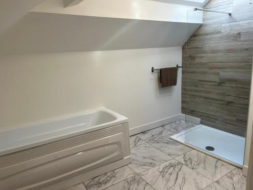 baño con bañera y pared de azulejos en King Street Apartments en Southport