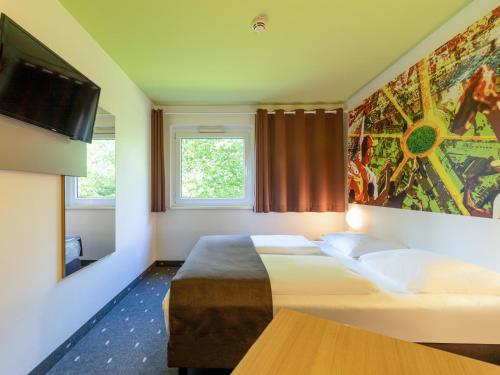 a hotel room with a bed and a flat screen tv at B&B HOTEL Dortmund-Messe in Dortmund
