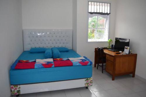 een slaapkamer met een bed, een bureau en een computer bij Rumah Inyiak Aguang in Baso
