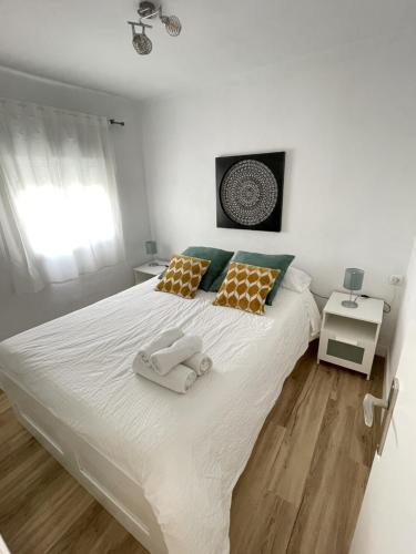 1 dormitorio con 1 cama blanca grande y 2 toallas en FEDRIANI Bright and cosy apartment en Sevilla