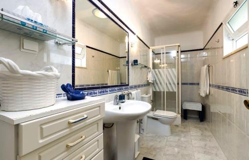 een badkamer met een wastafel, een toilet en een spiegel bij Casa Rosfra in Carvoeiro