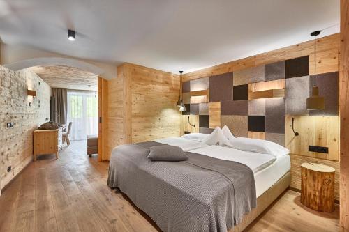 サン・カッシアーノにあるHotel Fanesの白い大型ベッドと木製の壁が備わるベッドルーム1室が備わります。