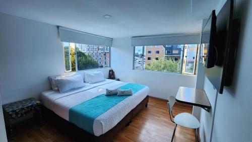a bedroom with a bed and two windows at Hotel Blue Zafiro in Bogot&aacute;