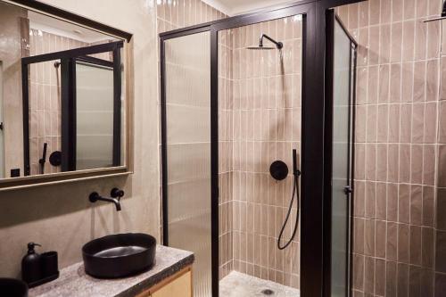 a bathroom with a shower with a sink and a mirror at Mosaics Athens Boutique Apartments in Athens