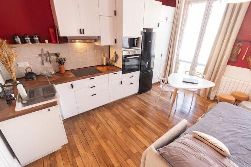 une cuisine avec des armoires blanches et une table dans une pièce dans l'établissement Immeuble L'Aristocrate - L'Epicurien- Bd Carnot, à Angers