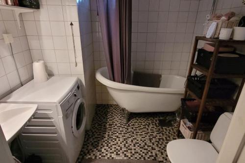 ein Badezimmer mit einer Badewanne und einer Waschmaschine in der Unterkunft Lägenhet i villa in Bålsta