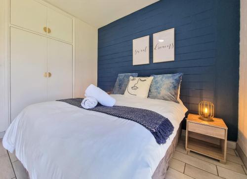 a bedroom with a blue accent wall and a bed at La Ballito 305 in Ballito