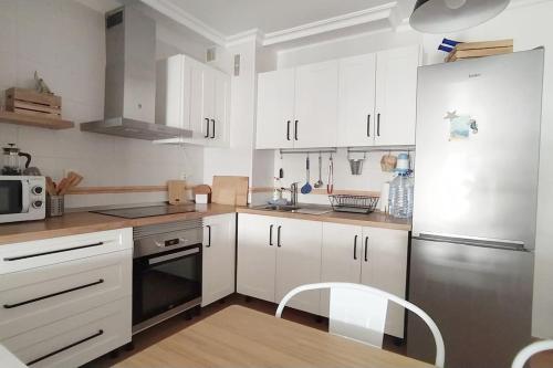 una cucina con armadi bianchi e frigorifero in acciaio inossidabile di Apartamento El Faro, Sotavento, playa la tejíta a La Tejita