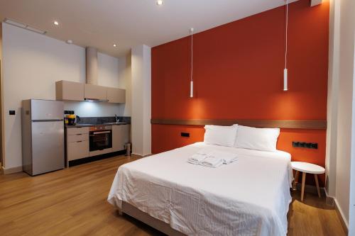a bedroom with a white bed and a kitchen at K2 Suites Kalamata in Kalamata