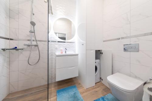 a white bathroom with a shower and a toilet at Apartament SUNLIGHT by Major Domus Club in Dziwnów