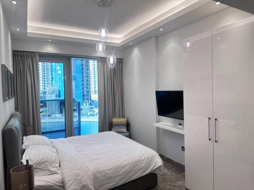 a white bedroom with a bed and a television at Tranquil Studio Marina View in Dubai