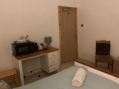 a room with a bed and a microwave and a desk at Broadwalk7 in Coltishall