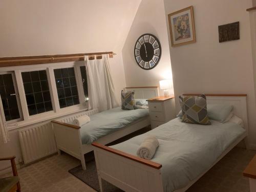 a bedroom with two beds and a clock on the wall at Broadwalk7 in Coltishall