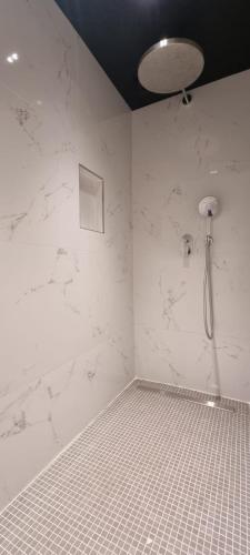 a bathroom with a shower with white marble walls at Suite privée avec sauna et spa à Saint-Fuscien in Saint-Fuscien