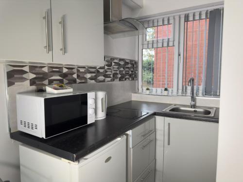 a kitchen with a microwave and a sink at Hills View Apartments in Manchester