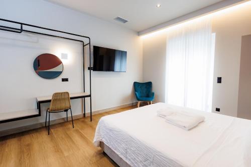 a bedroom with a bed and a tv and two chairs at K2 Suites Kalamata in Kalamata