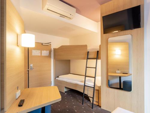 デュッセルドルフにあるB＆B ホテル デュッセルドルフ エアポートの二段ベッド1組、デスクが備わる小さな客室です。