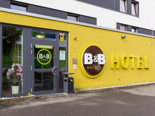 デュッセルドルフにあるB＆B ホテル デュッセルドルフ エアポートの黄色の建物(bdbホテルの看板付)