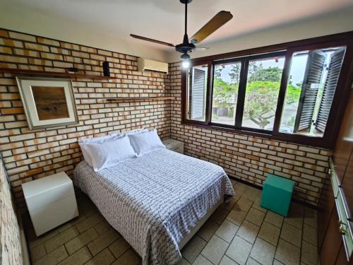 1 dormitorio con cama y pared de ladrillo en Casa para 10 pessoas a 150m da praia - C130, en Florianópolis