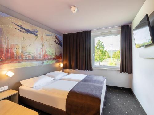 a hotel room with a bed and a window at B&B Hotel Düsseldorf-Airport in Düsseldorf