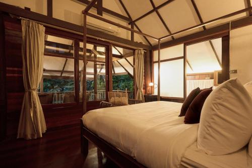 a bedroom with a bed in a room with windows at Jambolan Chiangmai in Chiang Mai
