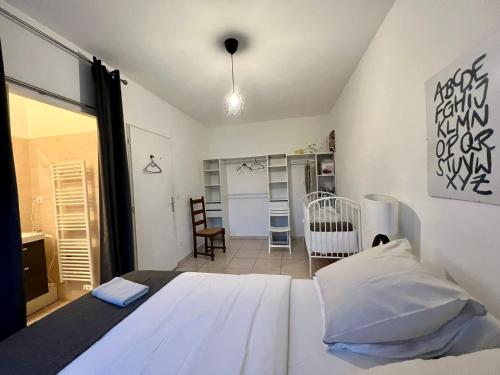 a bedroom with a white bed and a crib at Sully-sur-loire: Agréable maison en centre ville in Sully-sur-Loire