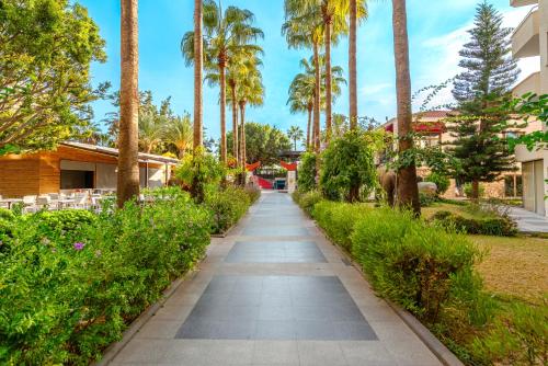 a walkway through a park with palm trees at SUN HEAVEN FAMILY & SPA in Alanya
