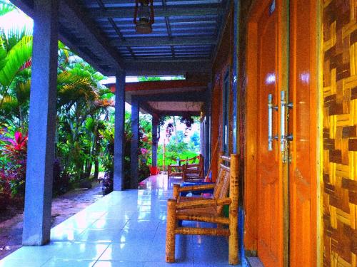 Eltari Homestay في تيتيباتو: شرفة للمبنى مع مقاعد خشبية