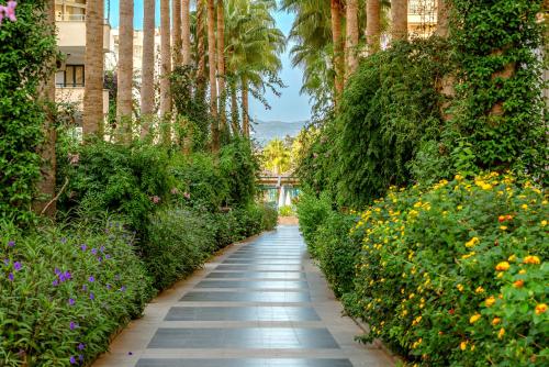 a walkway through a garden with flowers and palm trees at SUN HEAVEN FAMILY & SPA in Alanya