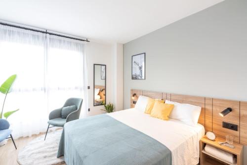 1 dormitorio blanco con 1 cama y 1 silla en Be Casa - Valdebebas, en Madrid