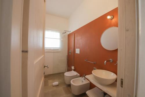 een badkamer met een wastafel, een toilet en een spiegel bij Trulli Dimore - Villa Coco in Ostuni