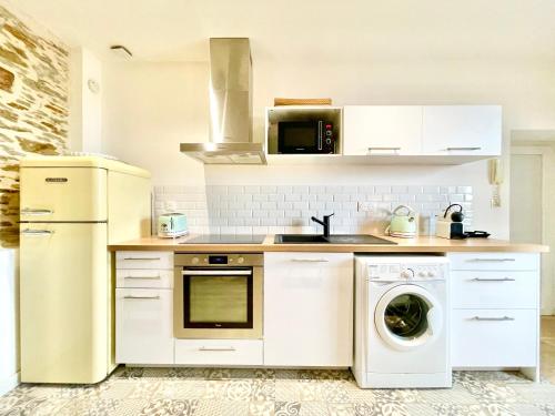 eine Küche mit weißen Geräten, einer Waschmaschine und einem Trockner in der Unterkunft Nantes - Le Bellamy - Authentique - Proche Centre Ville in Nantes