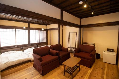 a living room with a bed and two chairs and a couch at GLOCE西会津 ふくの屋 l 古きを知り新しきを愉しむ l 築110年超の古民家が綴る心地よい宿 in Yanaizu