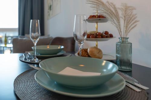a table with a bowl and plates and wine glasses at Modernes Apartment am Gleispark in Oldenburg