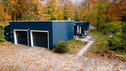 un edificio azul con dos puertas de garaje en el bosque en earthship forest exile, 