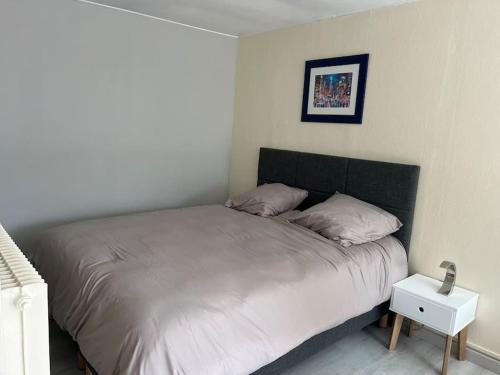 - une chambre avec un grand lit et une table de nuit dans l'établissement Le Puits du Village, à Mont-Saint-Aignan